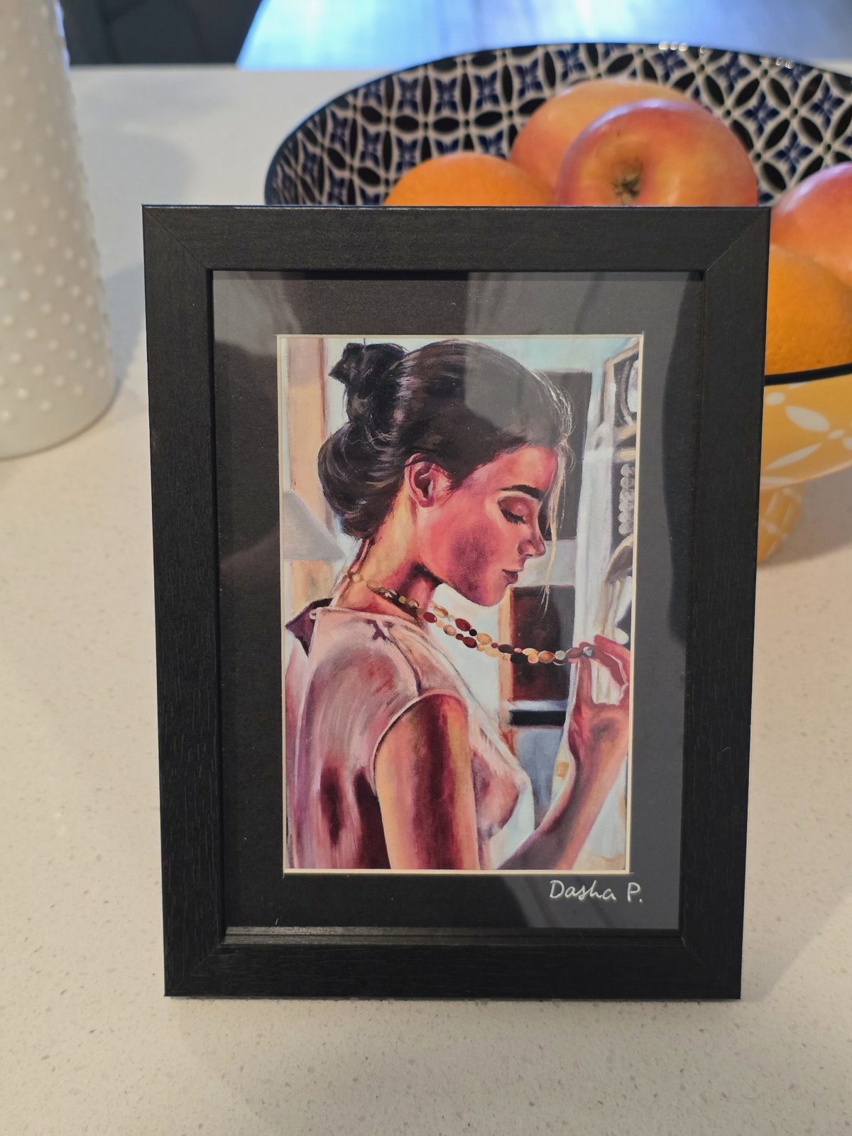 A Memory signed matted framed art print by Dasha Prudnikova, showing a woman in profile holding a necklace in a black frame with dark mat.